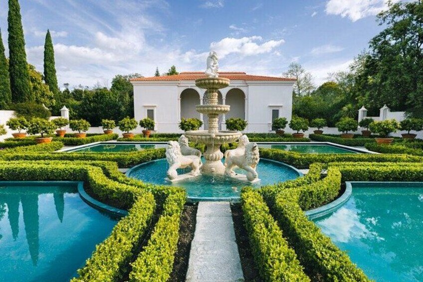 A landscaped garden with a fountain, manicured hedges, and a pool. 4
