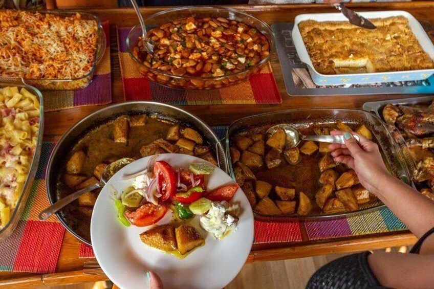 A table with various dishes including a plate with a salad, a casserole, and a tray of roasted potatoes. 4
