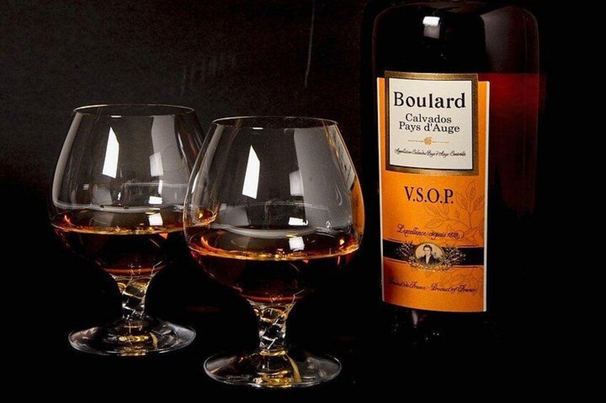 Two wine glasses filled with red wine and a bottle of Boulard Calvados wine. 1