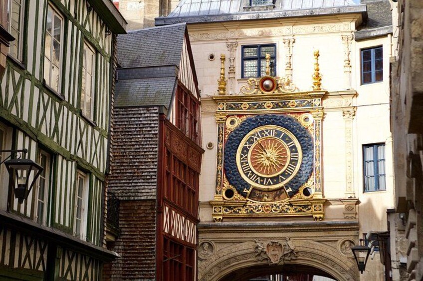 A historic building with a large ornate clock, half-timbered architecture, and a stone archway. 3