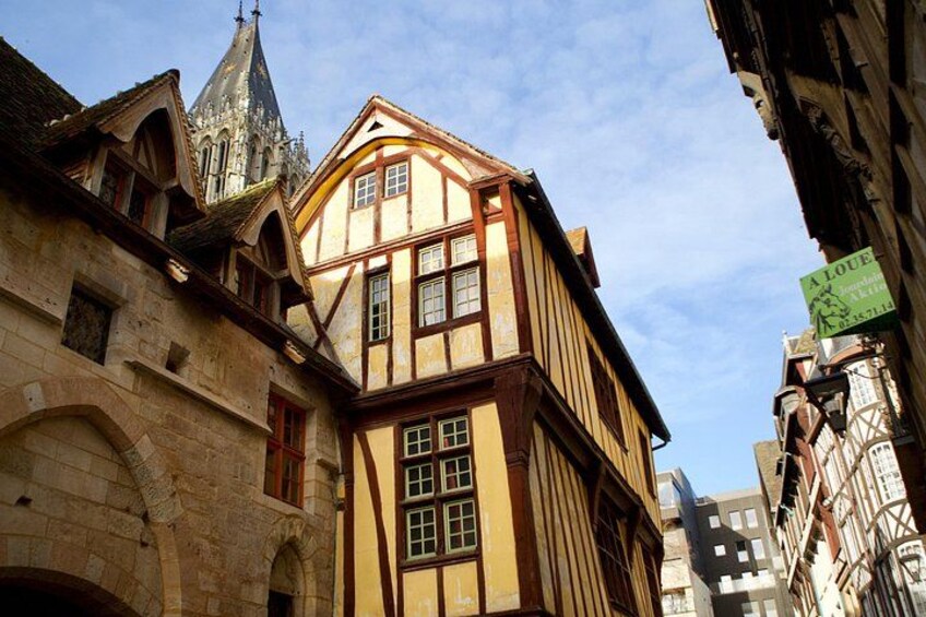 A historic building with a steep roof and a tower, surrounded by other traditional architecture. 5