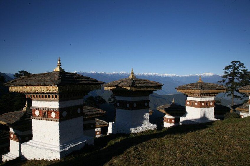 A row of traditional Tibetan prayer wheels with snow-capped mountains in the background. 3