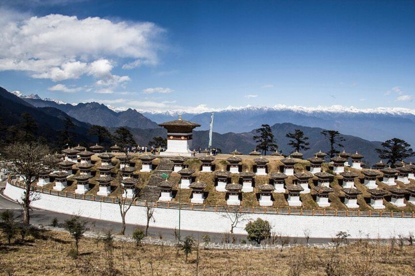 A traditional Tibetan monastery with a central stupa, surrounded by prayer flags and snow-capped mountains in the background. 3