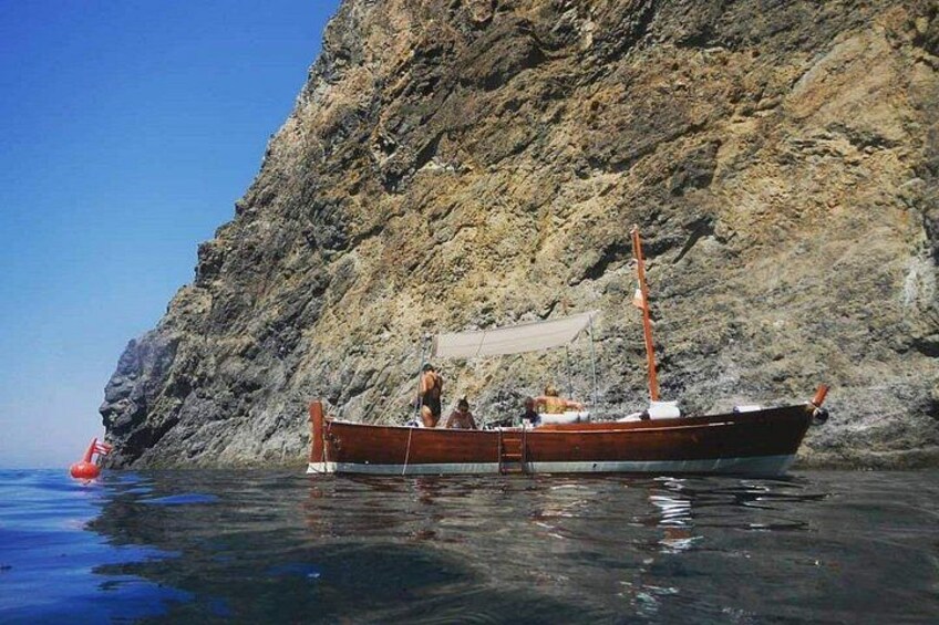 Un barco de madera anclado cerca de un acantilado rocoso junto al mar. 3