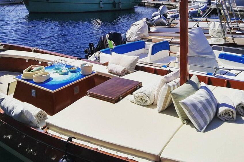 Cubierta de barco con asientos, una mesa y una alfombra pequeña. 4
