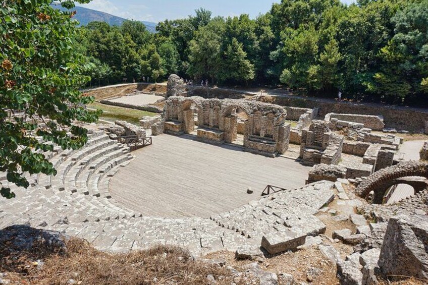 An ancient amphitheater with stone seating and ruins. 5