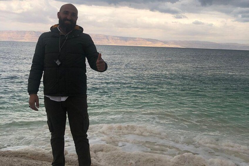 A person standing by a body of water with cliffs in the background. 4