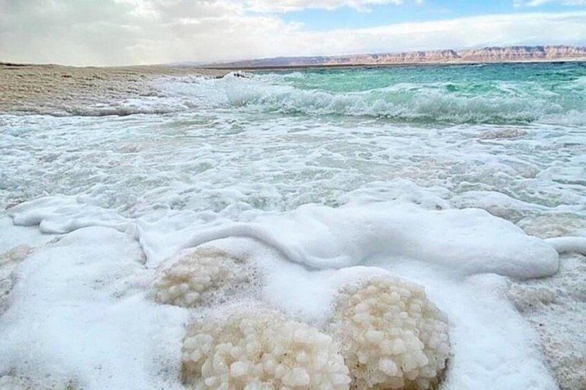 A beach with foamy waves and a distant shoreline. 5