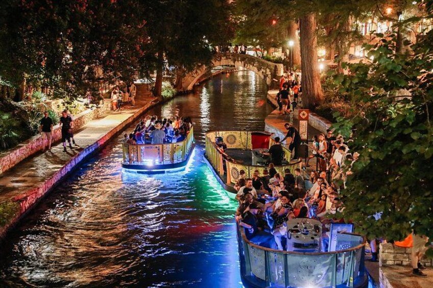 A nighttime canal scene with illuminated boats and people walking along the banks. 4