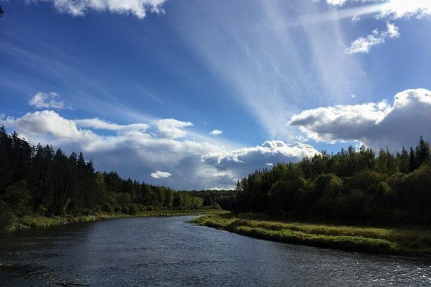 Een rivier die door een bebost landschap stroomt, met een heldere lucht. 5