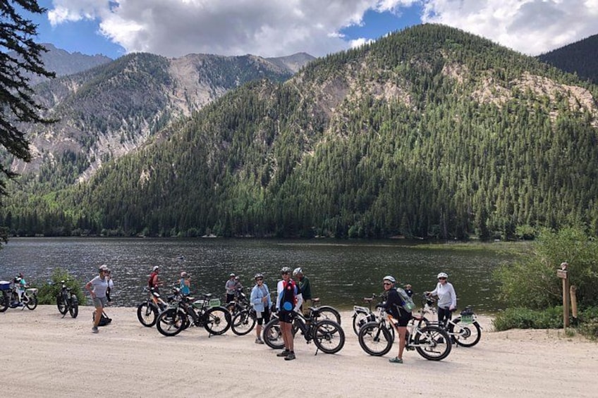 Un gruppo di ciclisti vicino a un lago con montagne sullo sfondo. 1