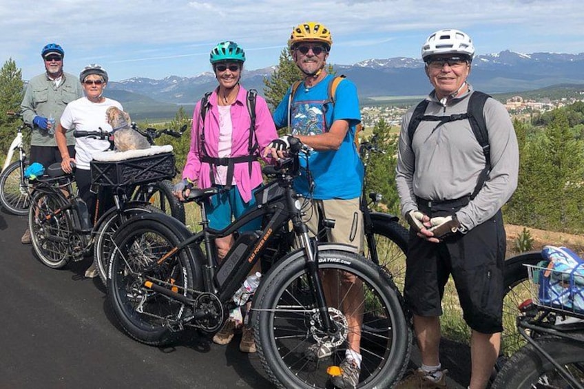 Un gruppo di ciclisti con biciclette, un cane e un suggestivo scenario montano. 3