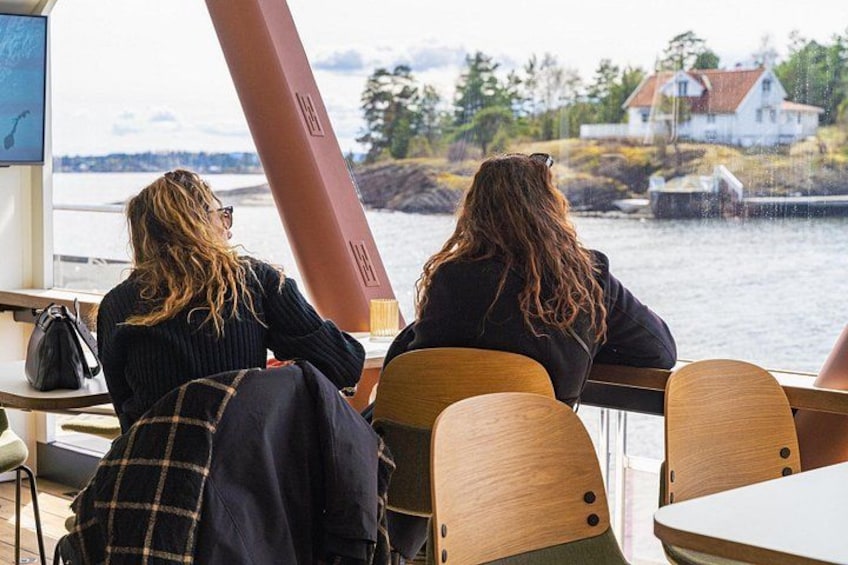 Two people sitting at a table by a window overlooking a body of water with houses in the background. 5