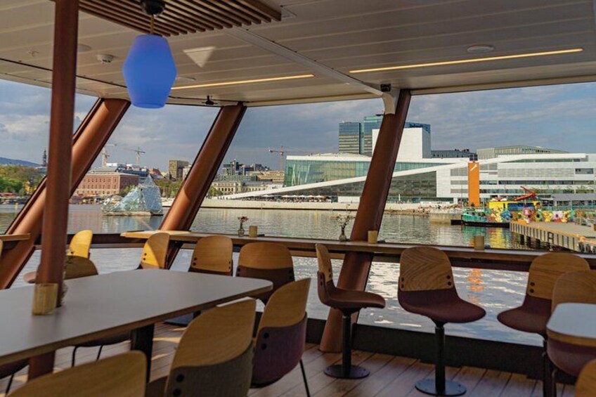 A dining area with tables and chairs, a view of a cityscape, and a body of water. 3