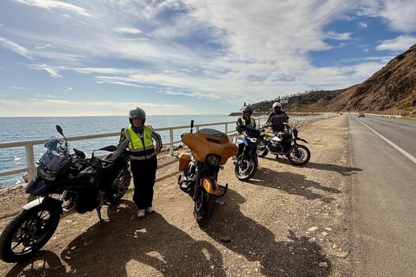 A coastal road with motorcycles parked along the side. 3