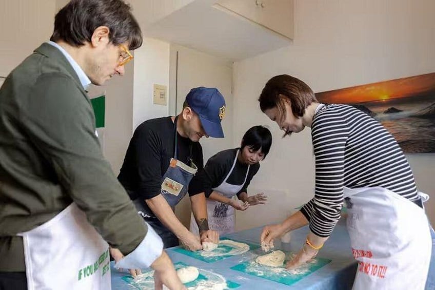 Vier Personen kochen gemeinsam und bereiten Essen an einem Tisch mit blauer Tischplatte zu. 2