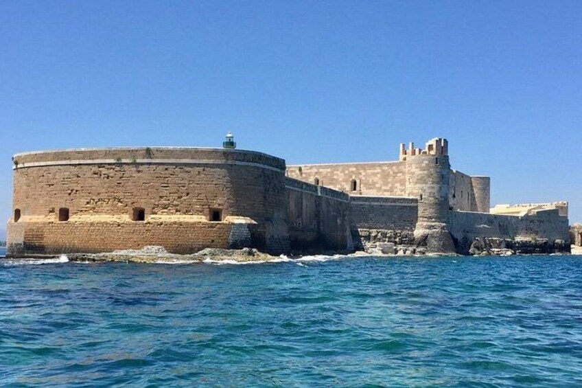 A coastal fortification with a round tower and a large wall, surrounded by the sea. 1