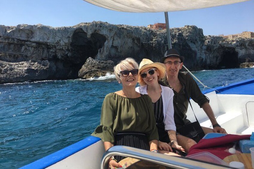 Three people on a boat with rocky cliffs in the background. 3