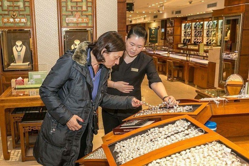 Zwei Personen betrachten Schmuck in einem gut beleuchteten Geschäft mit Holzetagen. 5