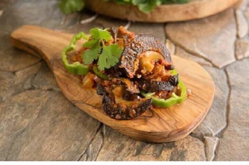 A wooden spoon with a dish containing grilled meat and vegetables. 5
