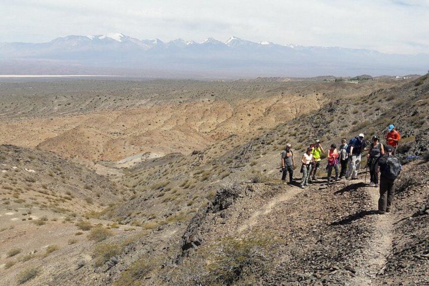 A group of hikers on a rocky trail with a mountainous backdrop. 1