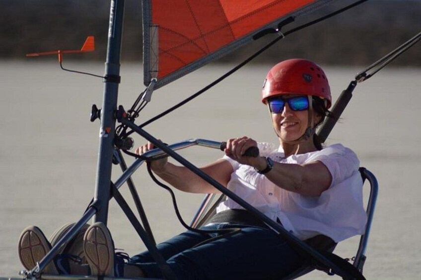 A person on a sailboat with a red sail, steering wheel, and a helmet. 5