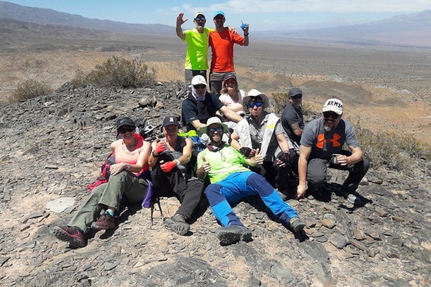 A group of people sitting on a rocky terrain with a desert landscape in the background. 3