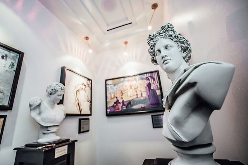 Una galería con esculturas clásicas y obras de arte enmarcadas en las paredes. 5