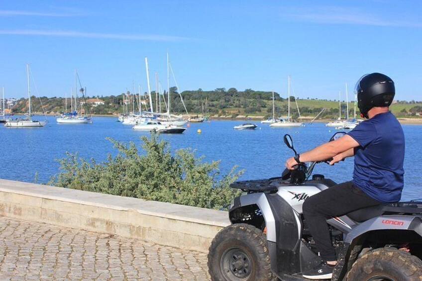 Una persona en un cuatrimoto observando un puerto deportivo con veleros. 5