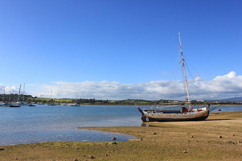 A calm harbor with a sailboat anchored near the shore, surrounded by calm water and a clear sky. 2