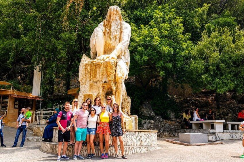 A group of people posing in front of a large stone statue of a seated figure. 5