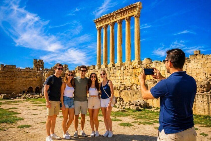A group of people taking a photo in front of ancient ruins with columns. 1