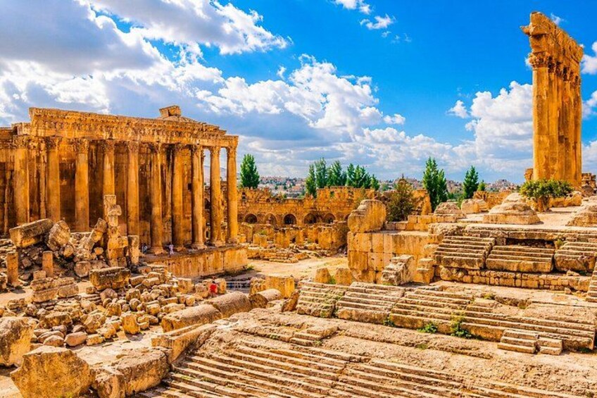 Ancient ruins with columns and a tall structure, set against a clear sky. 4