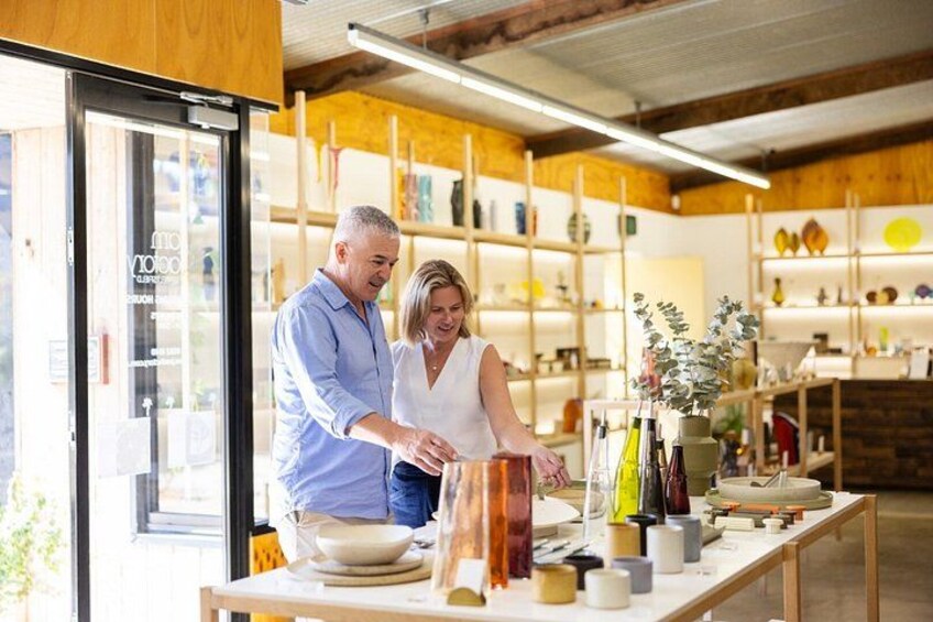 Two people in a kitchen with wooden shelves and various kitchenware. 2