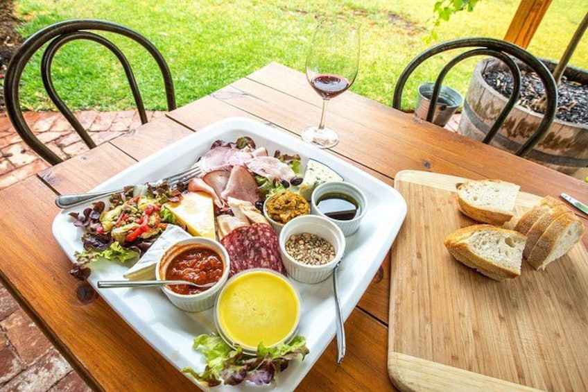 A wooden table with a charcuterie board, salad, bread, and wine. 1