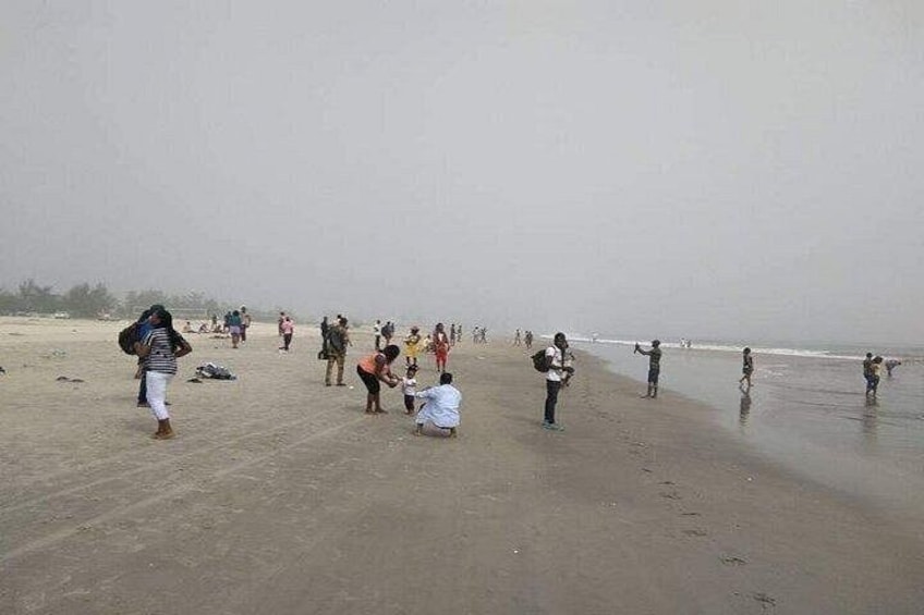 A beach with people walking and playing in the sand. 5