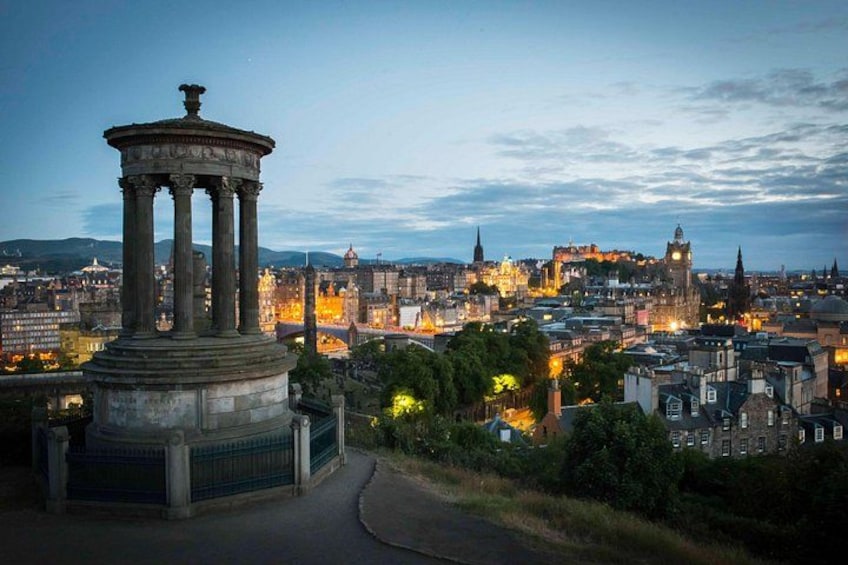 Une vue d’une ville au crépuscule, avec un monument historique important au premier plan et un château en arrière-plan. 3