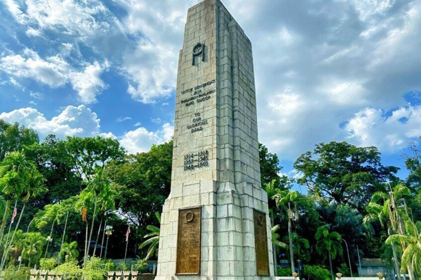 A tall monument with inscriptions, surrounded by lush greenery and trees. 2