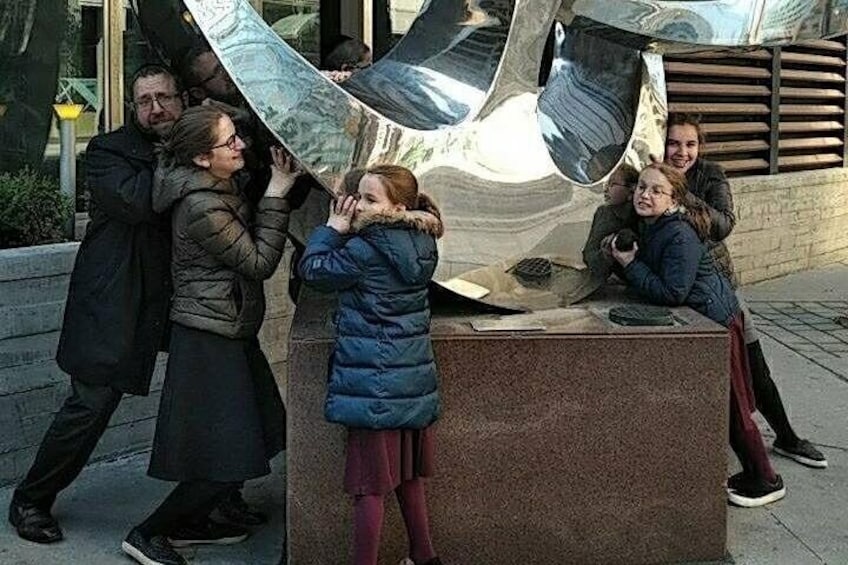 Un groupe de personnes interagissant avec une grande sculpture aux surfaces réfléchissantes. 5