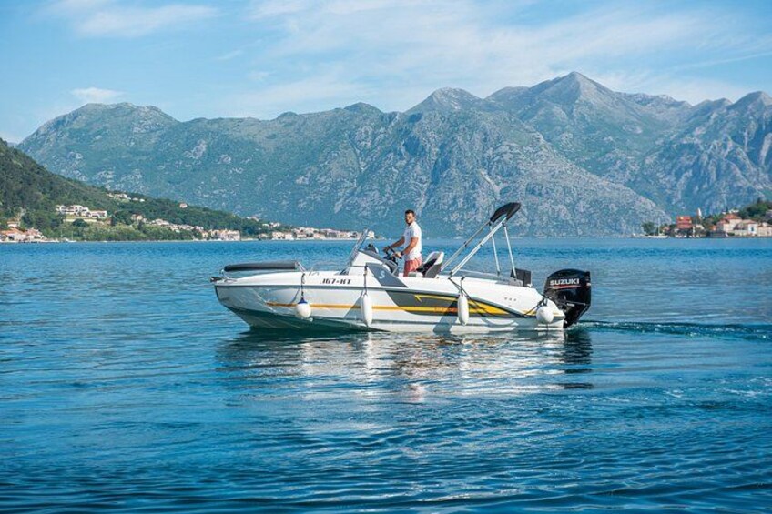Un bote con una persona, un motor y un paisaje montañoso al fondo. 4