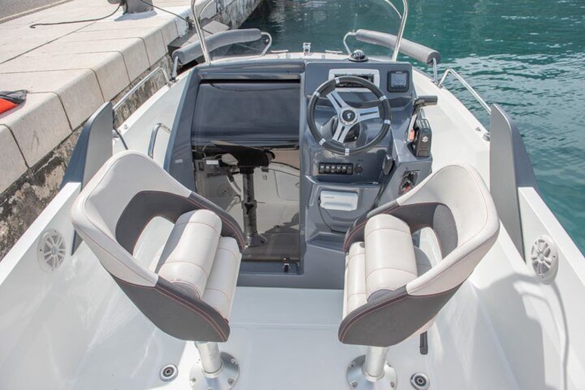 A boat's interior with a steering wheel, two seats, and a control panel. 3