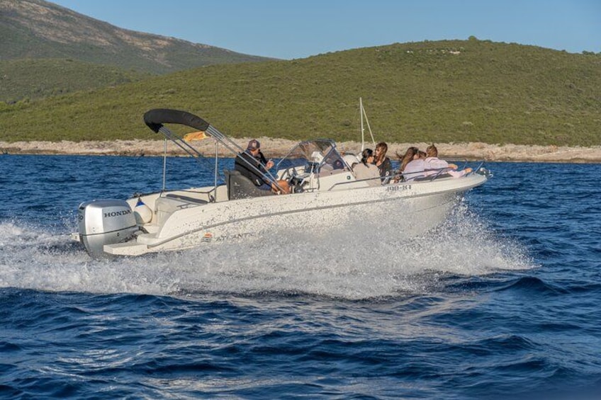 A white motorboat with a black canopy on the water, surrounded by people. 2