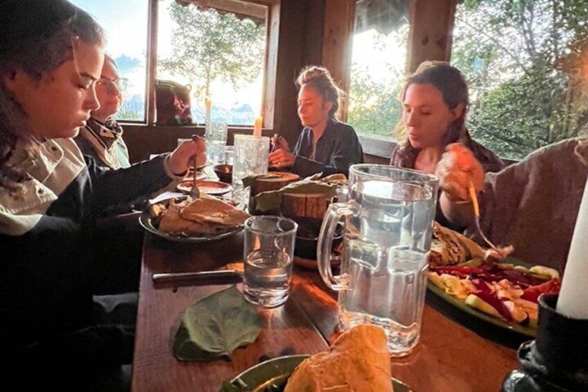 A group of people dining at a wooden table with food and drinks. 5