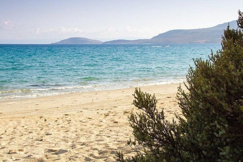 Une plage de sable, avec de l’eau et des montagnes qui se dessinent à l’horizon. 4