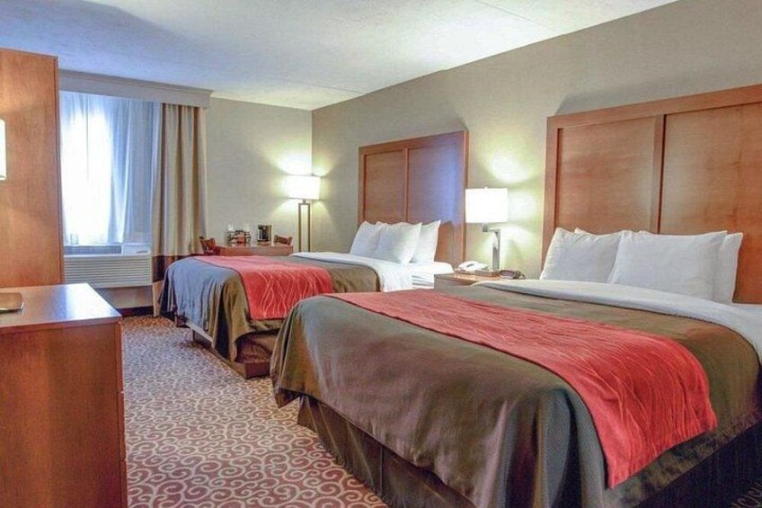 Een hotelkamer met twee bedden, een bureau en een lamp. 2