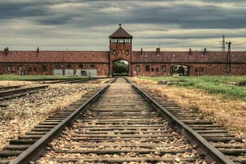 A railway track leading to a brick building with a tower. 1