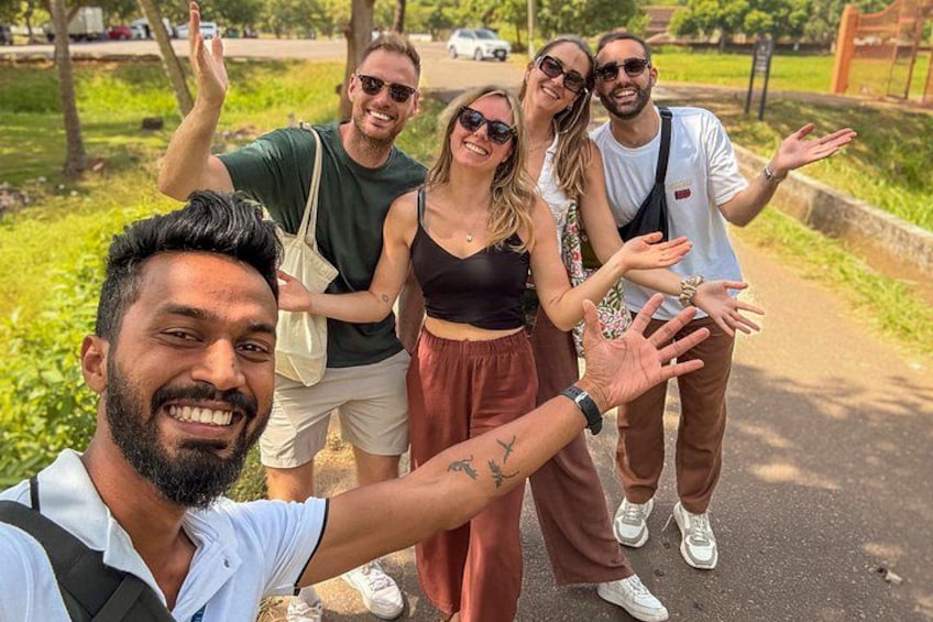 A group of people taking a selfie on a paved path in a park with greenery around. 4