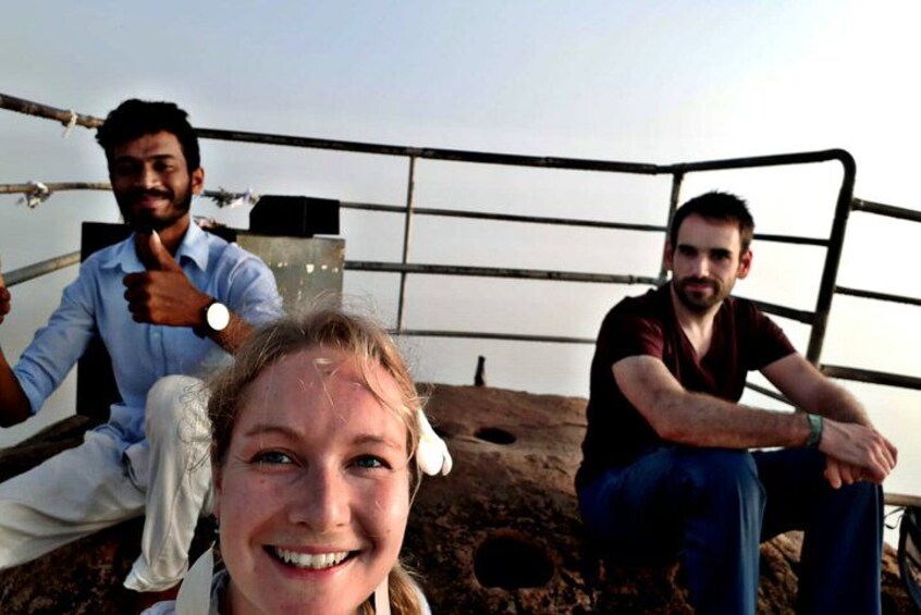 Three people sitting on a metal structure with a metal fence in the background. 2