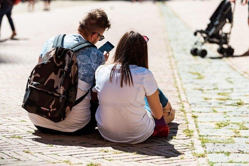 Dos personas sentadas en un sendero adoquinado, una con una mochila. 4