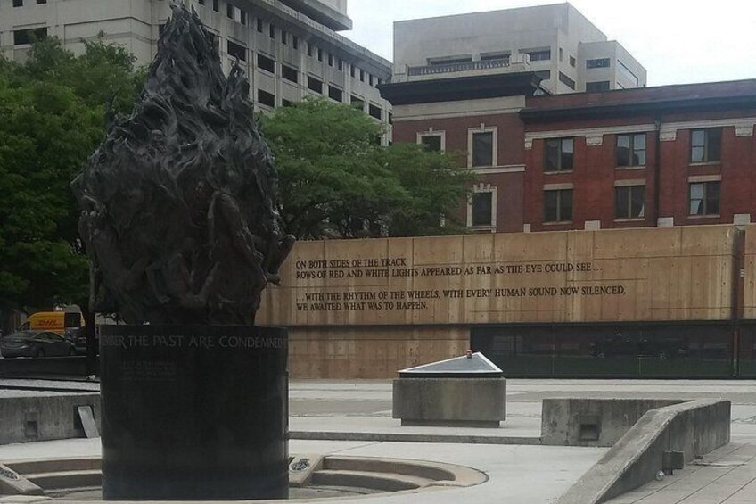 A sculpture of a lion in a city square with a large wall displaying text. 3